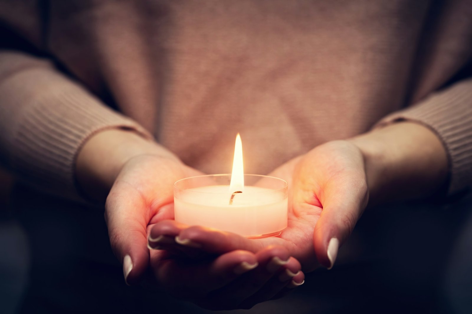 Candle light glowing in woman's hands. Praying, faith, religion