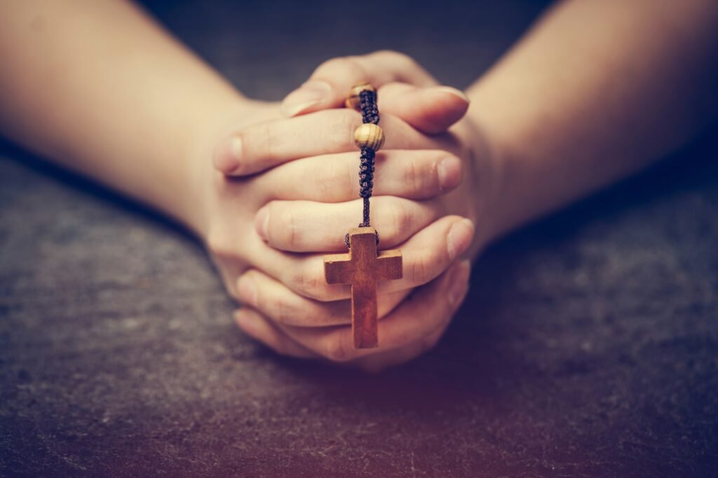 Woman praying with a rosary.